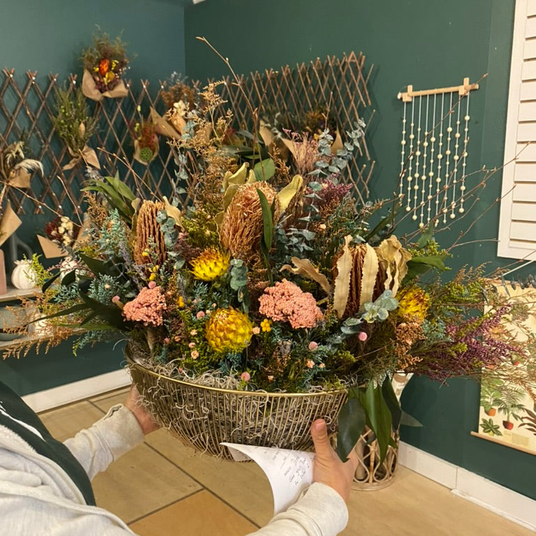 Person holding a large decorative floral arrangement against a green wall with decorative elements.